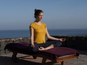 Frau meditiert vor dem Meer